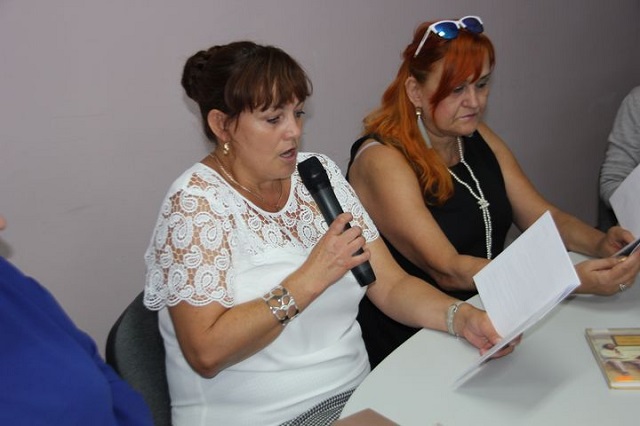 Dwie Panie uczestniczki wydarzenia, jedna z nich czyta trzymając mikrofon.