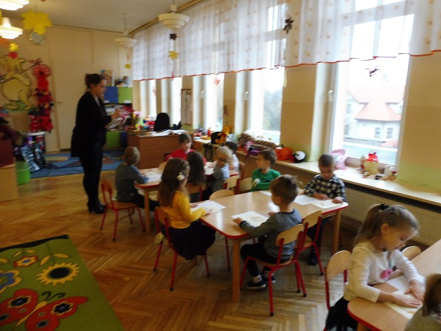 Dzieci w sali przedszkolnej siedzące przy stolikach
