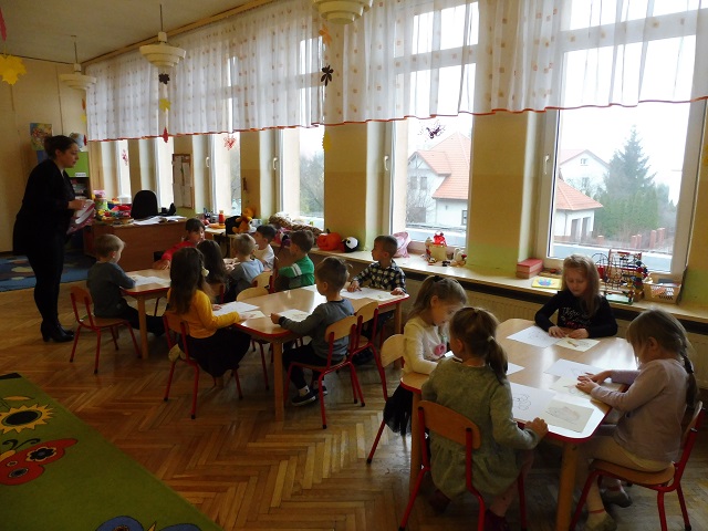 Dzieci w sali przedszkolnej siedzące przy stolikach